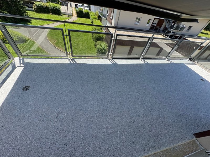 Balcon rénové en moquette de pierre gris clair, vue plongeante sur la résidence