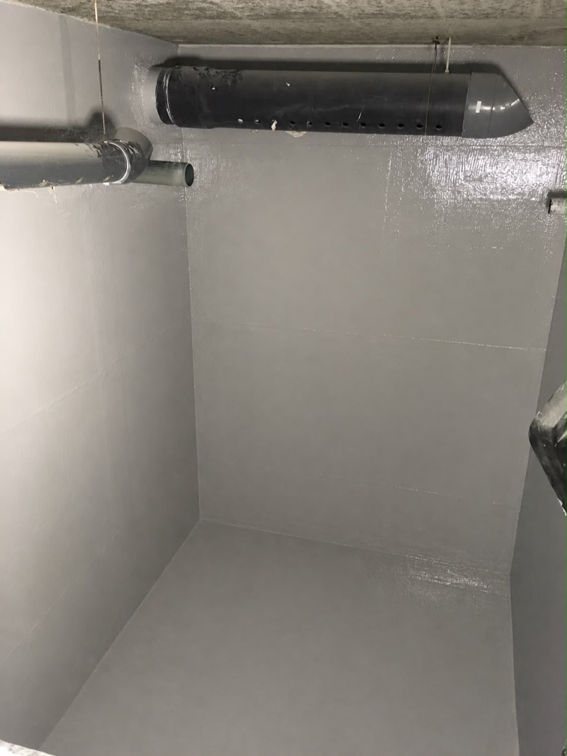 Cuve cuvelée en résine grise, canalisations reprises en plafond