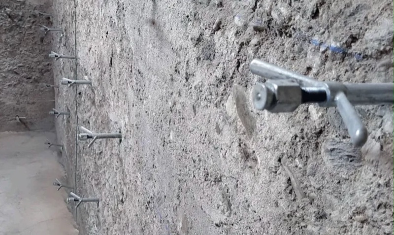 Injecteurs posés le long d’une fissure sur un mur en béton brut