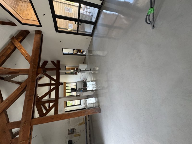 Séjour de chalet à charpente apparente avec sol en résine gris clair satiné