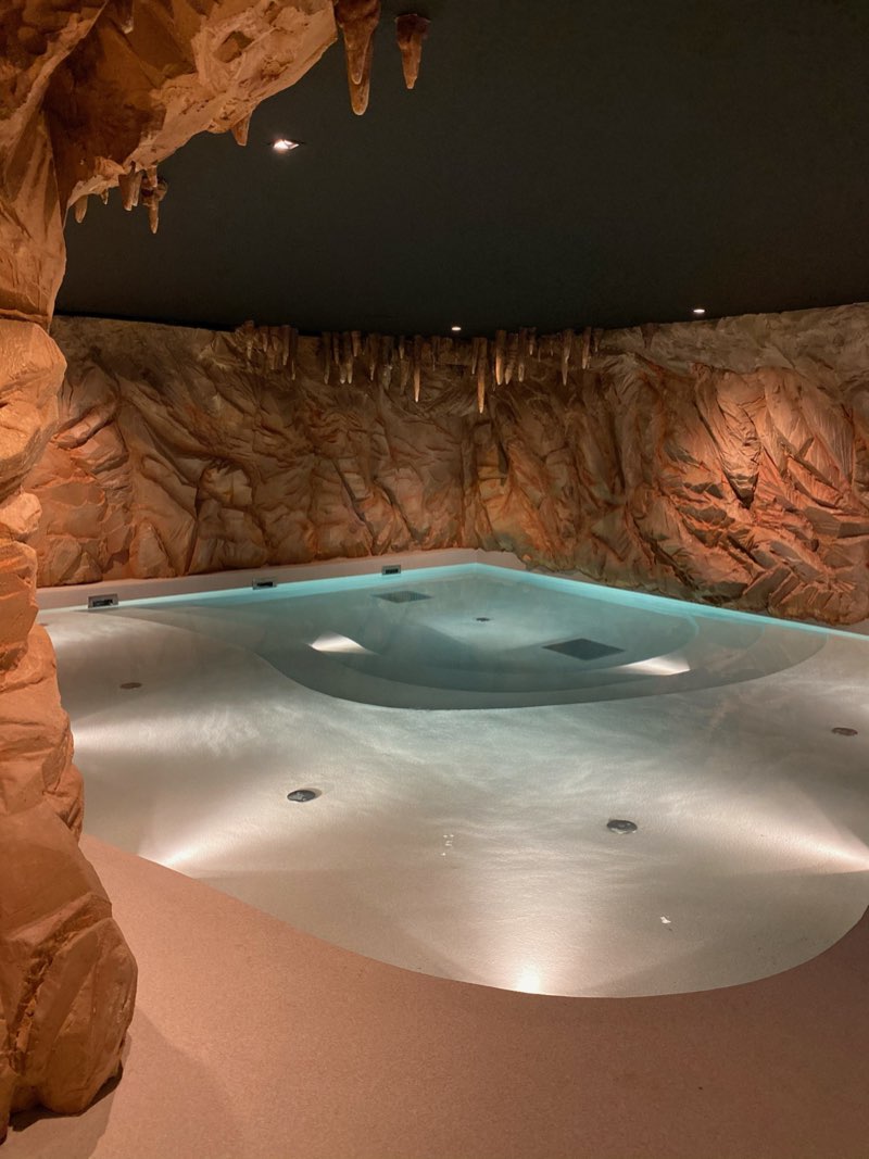 Bassin de spa intérieur au revêtement en résine clair dans un décor minéral